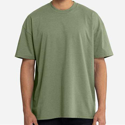 A person wearing an oversized short-sleeve crewneck t-shirt in sage green, shown from the neck down against a light gray background. Custom over size shirt print Next Level 7200