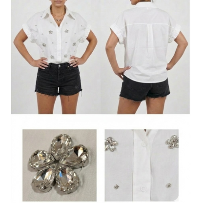 ​Front and back view of a woman wearing a white short-sleeve button-down shirt featuring crystal floral rhinestone embellishments, paired with black denim shorts. The image includes close-up shots of the 3D jewel flower appliqué and the crisp cotton fabric texture.